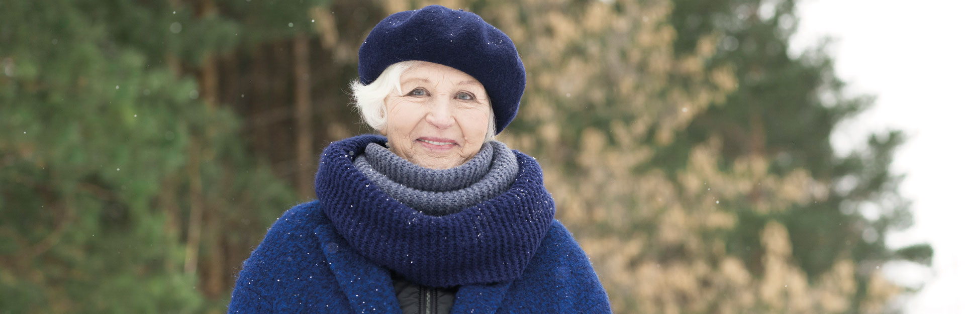 Elderly woman dressed warm in a hat, scarf and coat in cold, winter weather.