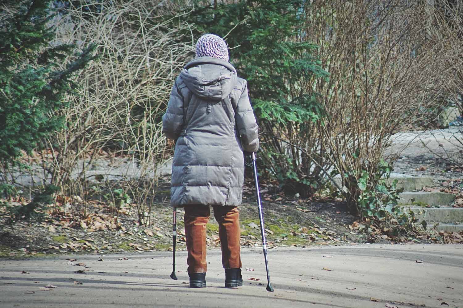 A woman walking wearing sturdy footwear and using a walking stick.