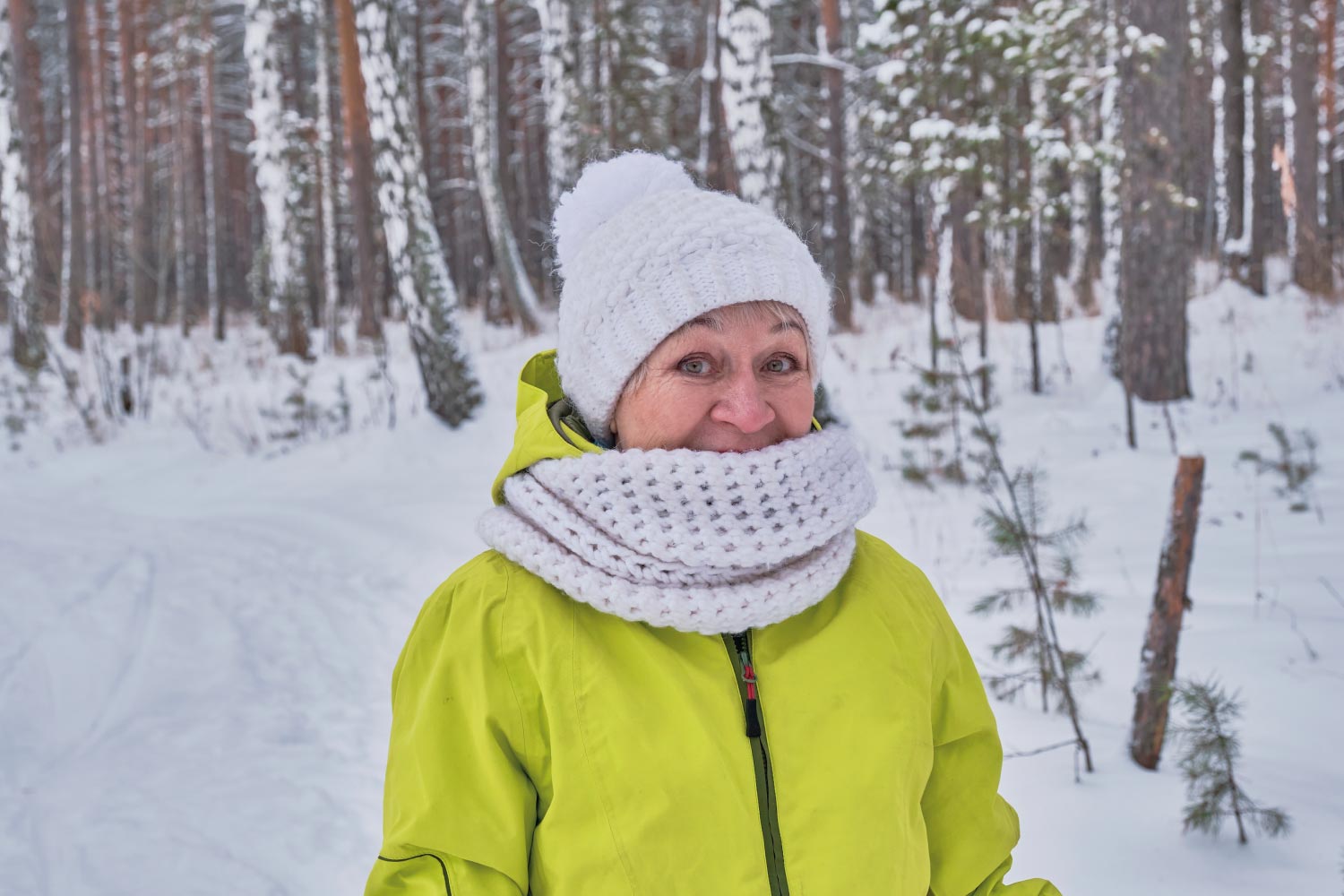 An older woman dressed warm and enjoying her time in the snow.
