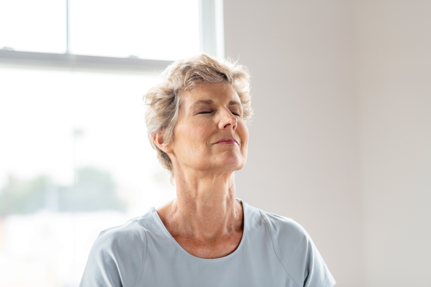 An older woman calmly meditating.